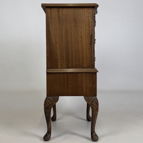 fig 6. A tall mahogany chest of drawers featuring four stacked drawers with brass handles, resting on carved cabriole legs with pad feet.