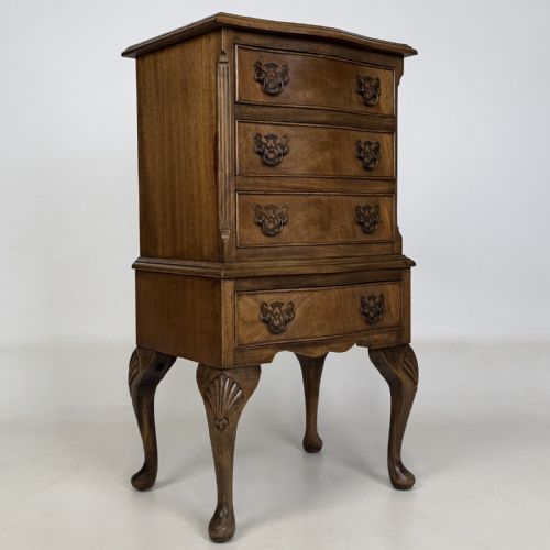 fig 7. A tall mahogany chest of drawers featuring four stacked drawers with brass handles, resting on carved cabriole legs with pad feet.