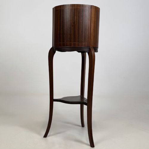 fig 1. An Edwardian mahogany plant stand featuring a deep cylindrical drum top with fine stringing inlay, supported on long cabriole legs joined by a lower triangular undertier.