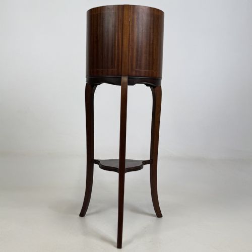 fig 2. An Edwardian mahogany plant stand featuring a deep cylindrical drum top with fine stringing inlay, supported on long cabriole legs joined by a lower triangular undertier.