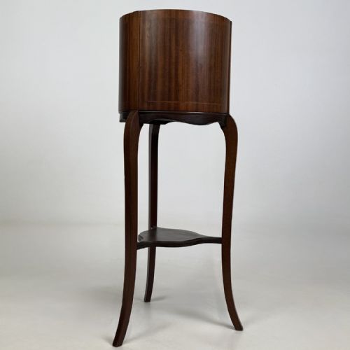 fig 3. An Edwardian mahogany plant stand featuring a deep cylindrical drum top with fine stringing inlay, supported on long cabriole legs joined by a lower triangular undertier.