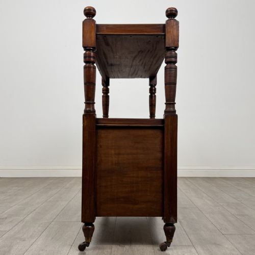 fig 2. A Victorian mahogany buffet trolley featuring an upper open shelf supported by turned column pillars over a lower two-door panelled cupboard set on brass castors.