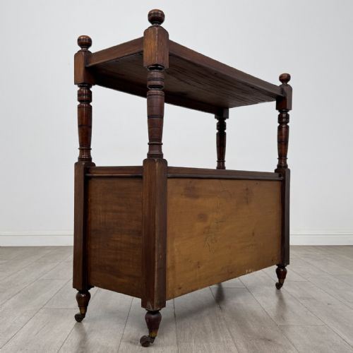fig 3. A Victorian mahogany buffet trolley featuring an upper open shelf supported by turned column pillars over a lower two-door panelled cupboard set on brass castors.