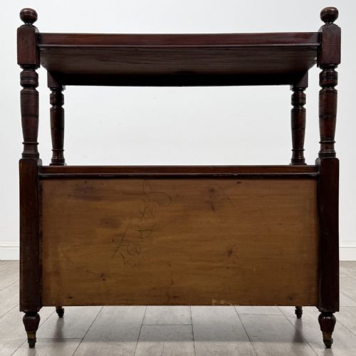 fig 4. A Victorian mahogany buffet trolley featuring an upper open shelf supported by turned column pillars over a lower two-door panelled cupboard set on brass castors.