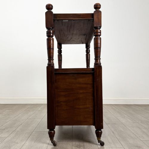 fig 6. A Victorian mahogany buffet trolley featuring an upper open shelf supported by turned column pillars over a lower two-door panelled cupboard set on brass castors.