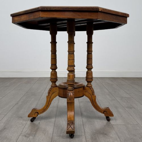 fig 1. A Victorian octagonal walnut side table featuring turned support columns, a central finial, and carved splayed legs with castors.