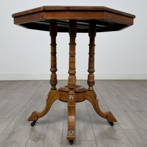 fig 3. A Victorian octagonal walnut side table featuring turned support columns, a central finial, and carved splayed legs with castors.