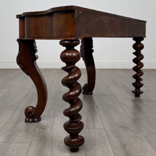fig 3. A Victorian mahogany console table with carved cabriole front legs, spiral rear legs, and a single drawer with round wooden handles.