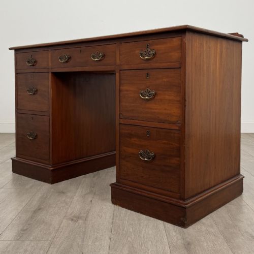 fig 1. A Victorian mahogany pedestal desk featuring nine drawers fitted with brass swan neck handles and a central kneehole, supported on plinth bases.