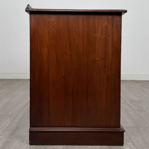 fig 6. A Victorian mahogany pedestal desk featuring nine drawers fitted with brass swan neck handles and a central kneehole, supported on plinth bases.