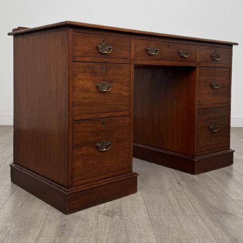 fig 7. A Victorian mahogany pedestal desk featuring nine drawers fitted with brass swan neck handles and a central kneehole, supported on plinth bases.