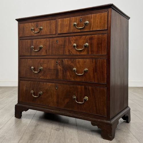 fig 1. An eighteenth-century Georgian mahogany chest of drawers featuring two short over three long graduated drawers with brass swan-neck handles and bracket feet.