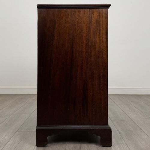 fig 6. An eighteenth-century Georgian mahogany chest of drawers featuring two short over three long graduated drawers with brass swan-neck handles and bracket feet.