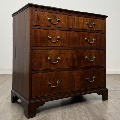 fig 7. An eighteenth-century Georgian mahogany chest of drawers featuring two short over three long graduated drawers with brass swan-neck handles and bracket feet.