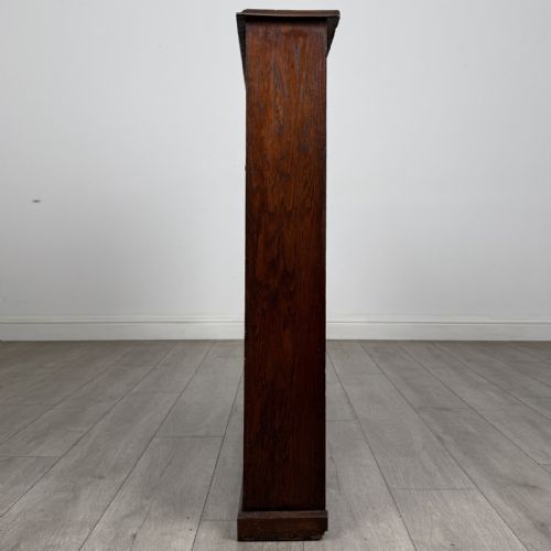 fig 2. A low Edwardian solid oak open bookcase featuring three wide shelves and a dark polished finish.