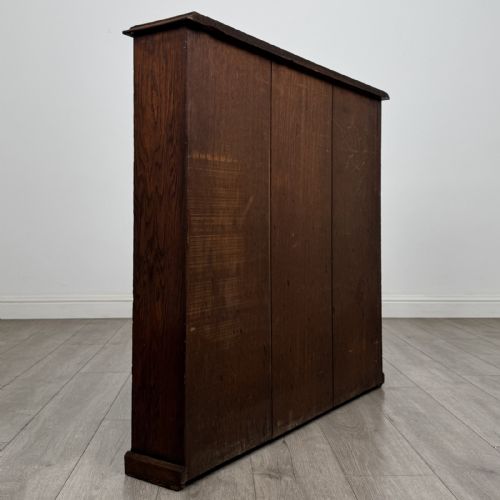 fig 3. A low Edwardian solid oak open bookcase featuring three wide shelves and a dark polished finish.
