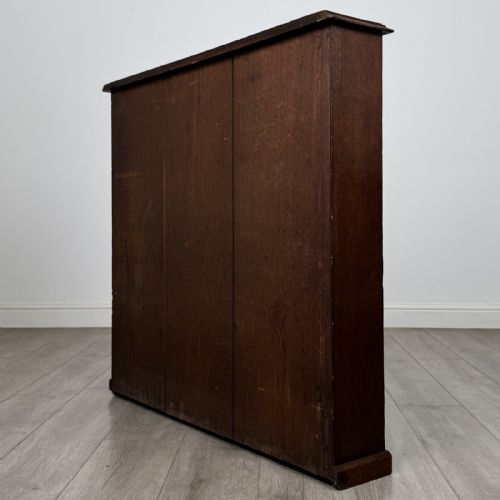 fig 5. A low Edwardian solid oak open bookcase featuring three wide shelves and a dark polished finish.