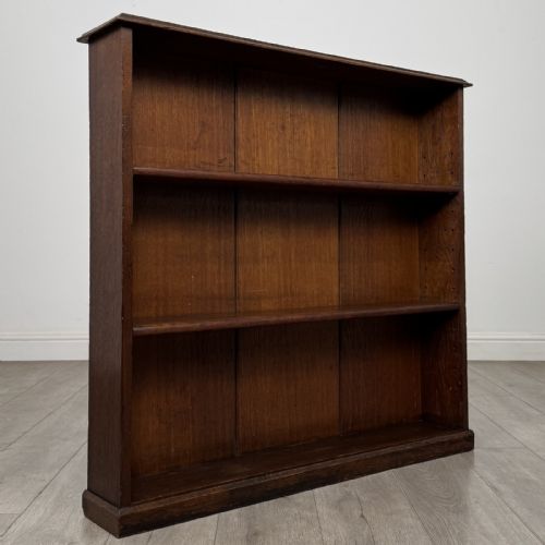 fig 7. A low Edwardian solid oak open bookcase featuring three wide shelves and a dark polished finish.
