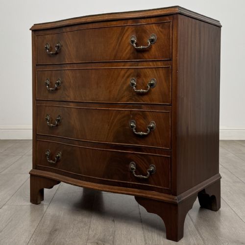 fig 1. A Georgian style mahogany serpentine chest featuring four graduated drawers with brass drop handles and bracket feet.