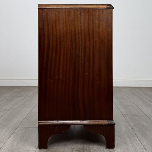 fig 6. A Georgian style mahogany serpentine chest featuring four graduated drawers with brass drop handles and bracket feet.