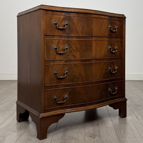 fig 7. A Georgian style mahogany serpentine chest featuring four graduated drawers with brass drop handles and bracket feet.