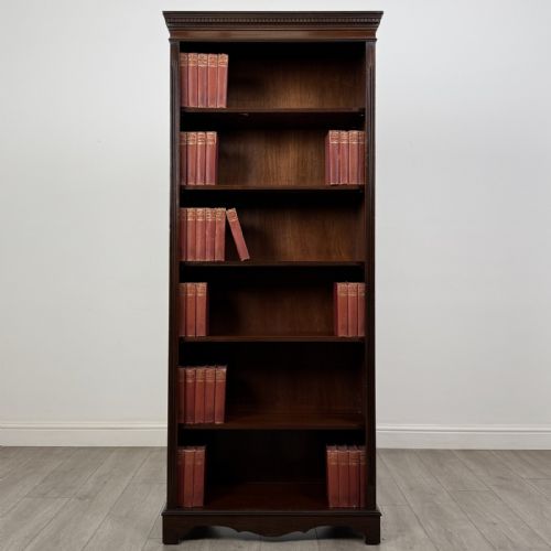 fig 1. A tall dark mahogany open bookcase featuring a dentil cornice, five fixed shelves, fluted side pilasters, and a shaped apron base.