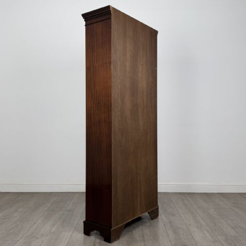 fig 4. A tall dark mahogany open bookcase featuring a dentil cornice, five fixed shelves, fluted side pilasters, and a shaped apron base.