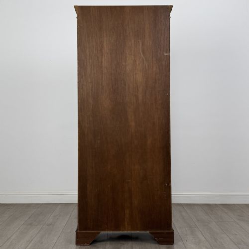 fig 5. A tall dark mahogany open bookcase featuring a dentil cornice, five fixed shelves, fluted side pilasters, and a shaped apron base.