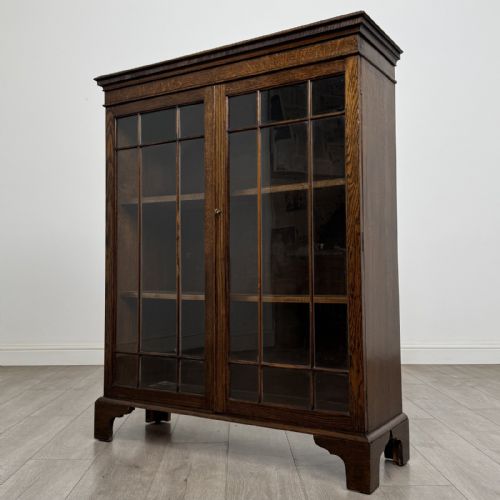 fig 2. A dark oak Georgian style display cabinet featuring twin glazed doors with rectangular timber mullions and bracket feet.