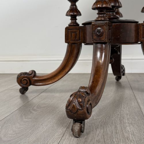fig 6. A Victorian burr walnut tilt-top loo table featuring an oval top supported by four turned columns and carved quadform legs with scroll feet.