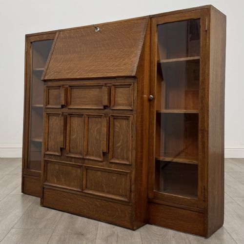 fig 3. An Art Deco oak side-by-side bureau bookcase with a central slant-front desk above panelled cupboards, flanked by two glazed display cabinets.