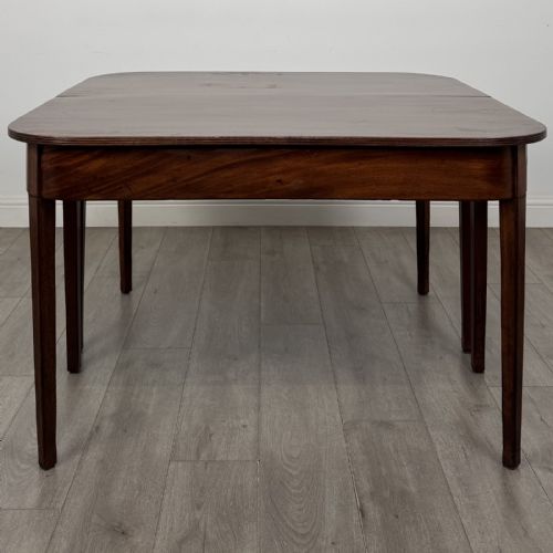 fig 2. An antique Georgian dark mahogany extending dining table featuring rounded D-end corners, a removable leaf, and square tapered legs.