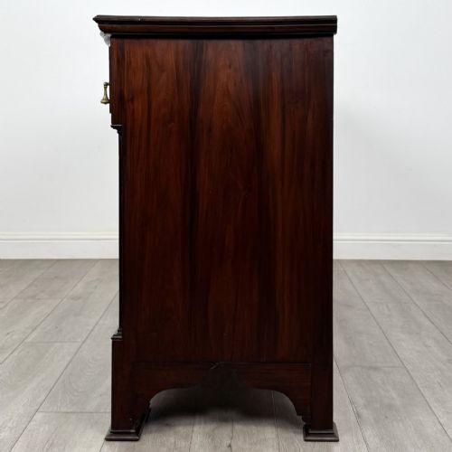 fig 2. An Edwardian dark mahogany bow-front sideboard featuring two drawers with brass drop handles over a double cupboard with carved details.