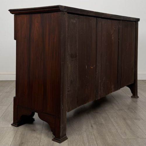 fig 3. An Edwardian dark mahogany bow-front sideboard featuring two drawers with brass drop handles over a double cupboard with carved details.