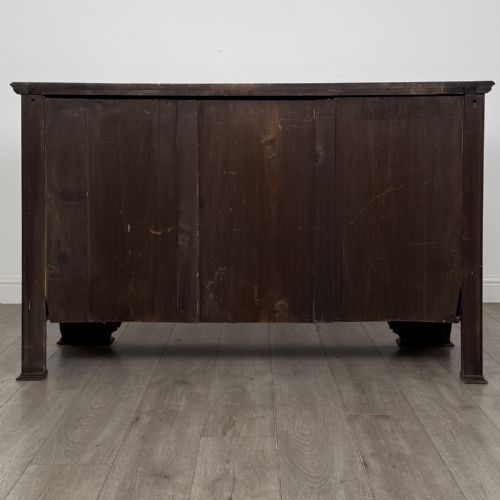 fig 4. An Edwardian dark mahogany bow-front sideboard featuring two drawers with brass drop handles over a double cupboard with carved details.