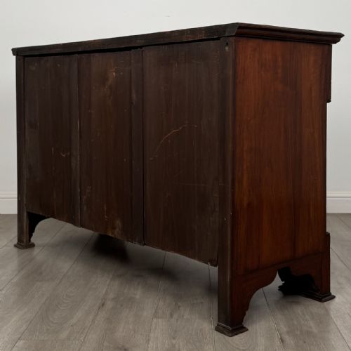 fig 5. An Edwardian dark mahogany bow-front sideboard featuring two drawers with brass drop handles over a double cupboard with carved details.