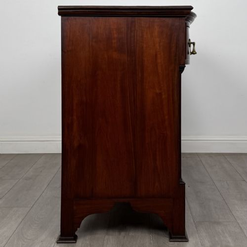 fig 6. An Edwardian dark mahogany bow-front sideboard featuring two drawers with brass drop handles over a double cupboard with carved details.