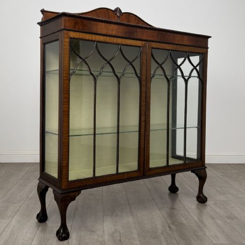 fig 7. A dark mahogany glazed display cabinet featuring gothic astragal door bars, a carved pediment top, and cabriole legs with ball and claw feet.