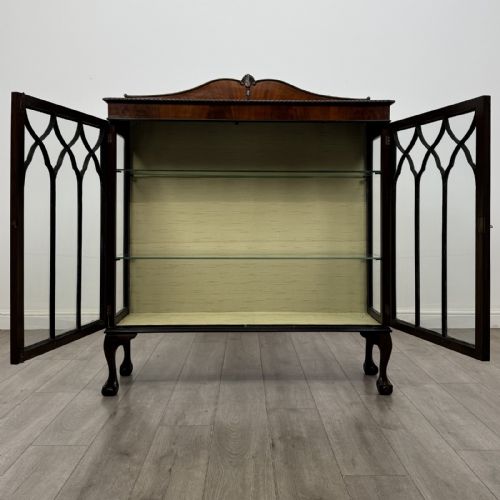 fig 8. A dark mahogany glazed display cabinet featuring gothic astragal door bars, a carved pediment top, and cabriole legs with ball and claw feet.