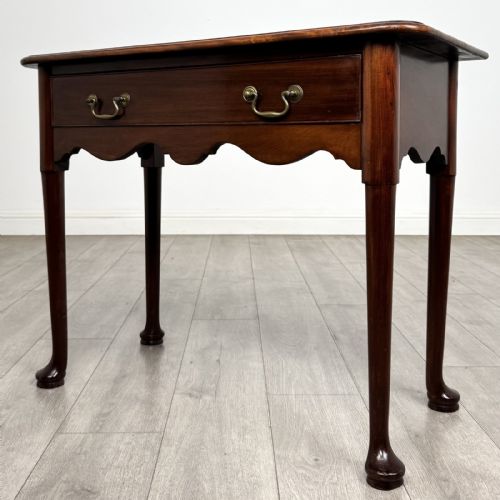 fig 1. An 18th-century Georgian mahogany side table featuring a single drawer with two brass swan-neck handles, a shaped frieze, and cabriole legs terminating in pad feet.