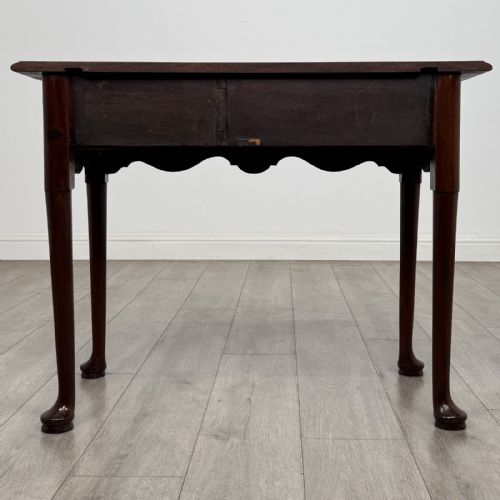 fig 4. An 18th-century Georgian mahogany side table featuring a single drawer with two brass swan-neck handles, a shaped frieze, and cabriole legs terminating in pad feet.