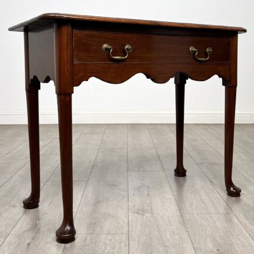 fig 7. An 18th-century Georgian mahogany side table featuring a single drawer with two brass swan-neck handles, a shaped frieze, and cabriole legs terminating in pad feet.