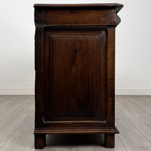 fig 6. A 19th-century French dark walnut sideboard featuring twin panelled doors with drop handles, flanked by fluted pilasters, with a carved winged cherub head centred on the frieze.