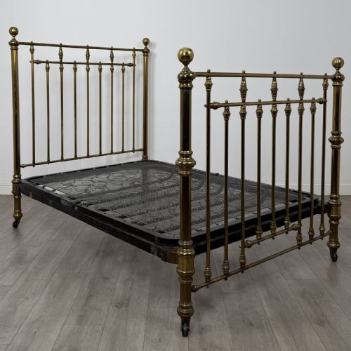fig 1. A Victorian brass double bed frame with turned vertical spindles, spherical ball finials on the corner posts, and castors on the feet.