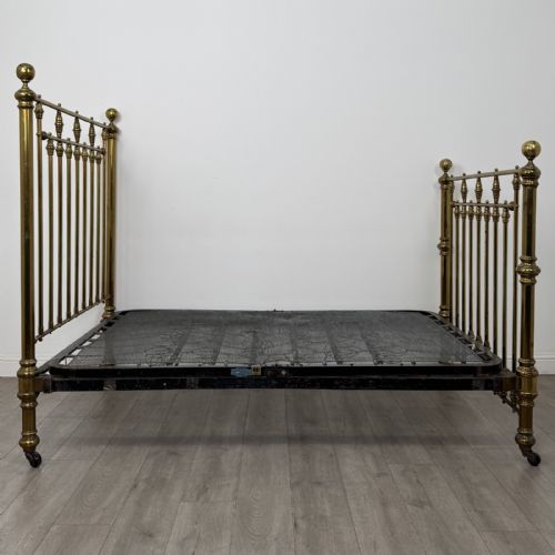 fig 2. A Victorian brass double bed frame with turned vertical spindles, spherical ball finials on the corner posts, and castors on the feet.