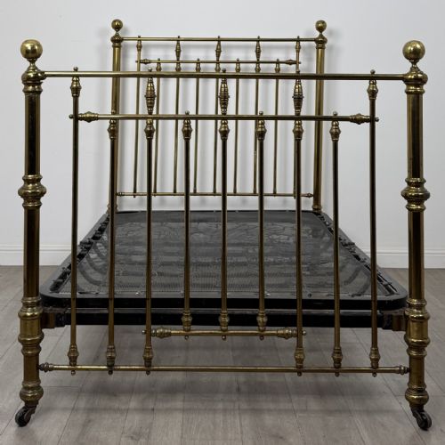 fig 3. A Victorian brass double bed frame with turned vertical spindles, spherical ball finials on the corner posts, and castors on the feet.