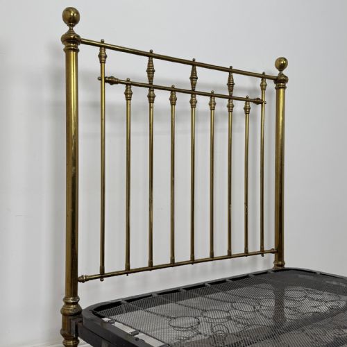 fig 4. A Victorian brass double bed frame with turned vertical spindles, spherical ball finials on the corner posts, and castors on the feet.