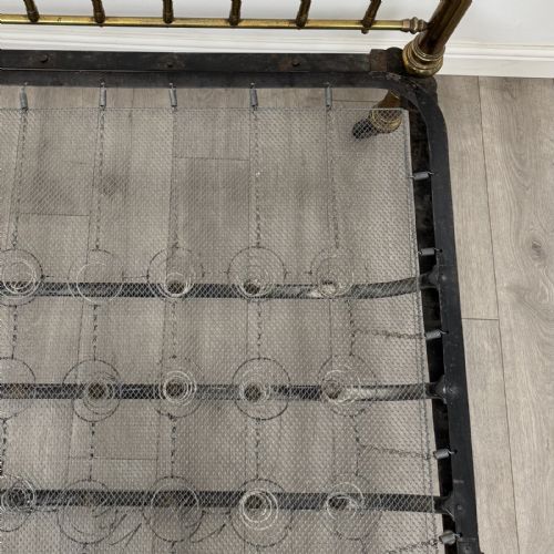 fig 5. A Victorian brass double bed frame with turned vertical spindles, spherical ball finials on the corner posts, and castors on the feet.