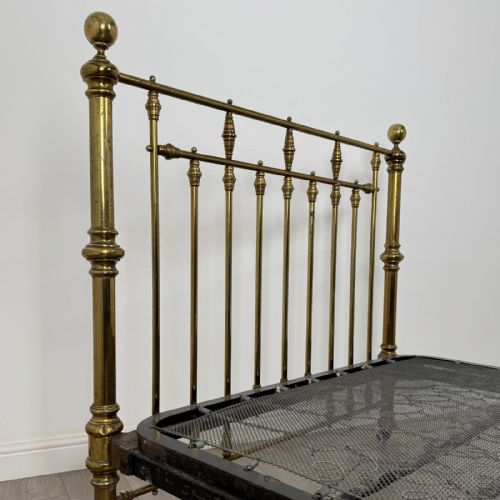 fig 7. A Victorian brass double bed frame with turned vertical spindles, spherical ball finials on the corner posts, and castors on the feet.