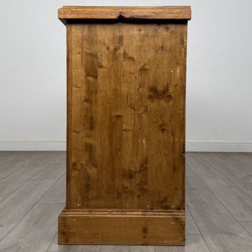fig 2. A vintage natural pine sideboard featuring three top drawers above three panelled cupboard doors with turned wooden knobs and a solid plinth base.